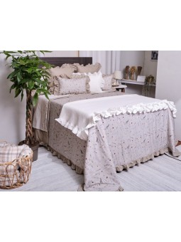 Funda de cojín con fondo en color beige arena y estampado de flores. Diseño lencero terminado en volante.