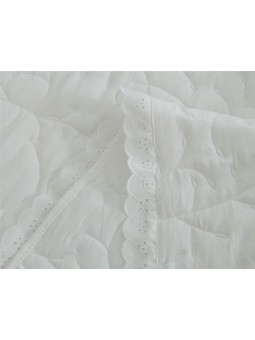 Colcha bordada con dibujo floral en color blanco y puntilla.