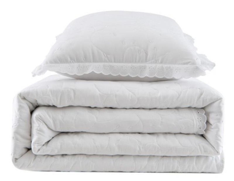 Colcha bordada con dibujo floral en color blanco y puntilla.