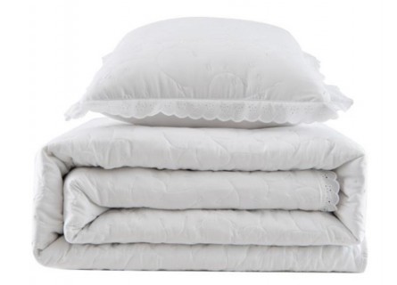 Colcha bordada con dibujo floral en color blanco y puntilla.