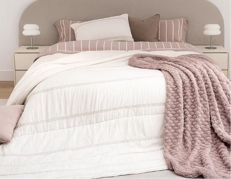 Edredón gris claro con bordado Tafel en composición de cama con accesorios de manta y cojines. Imagen ampliada