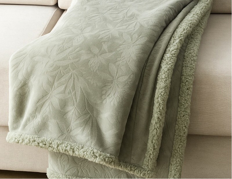 Manta Sanvi sobre sofá, color verde con textura en relieve.