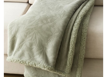 Manta Sanvi sobre sofá, color verde con textura en relieve.