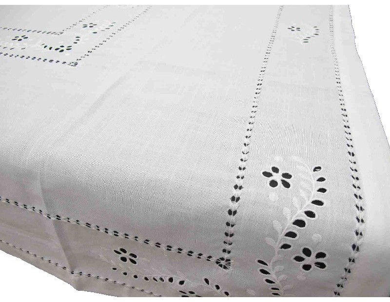 Mantel blanco bordado con dibujo calado de flor blanca.